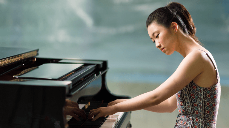 A teenage girl concentrates on playing the piano.