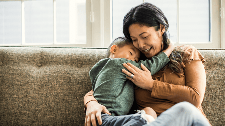 Mom holding son on a light green couch.