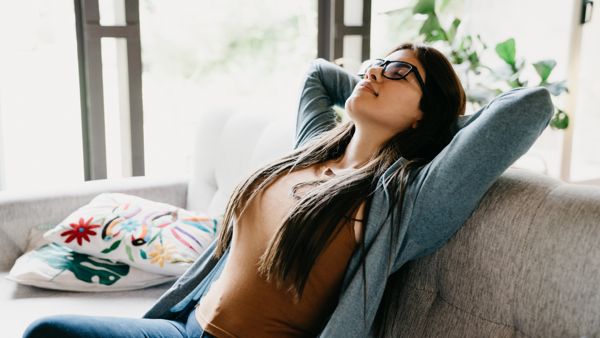 Young adult woman relaxing at home, sitting on the sofa.