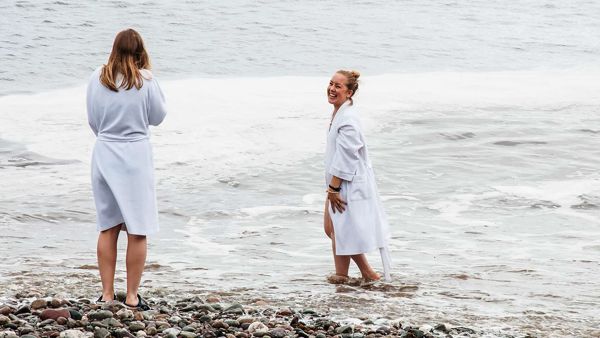 Two ladies in spa robes stand in the water at Spa Chance Harbour 