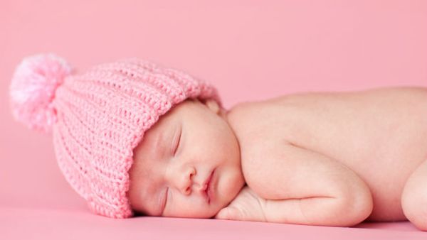 sleeping baby girl with pink hat and pink background