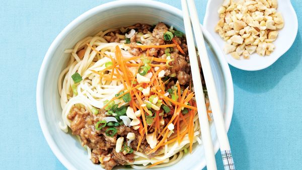 bowl of noodles with ground pork, shredded carrot, green onion and peanuts