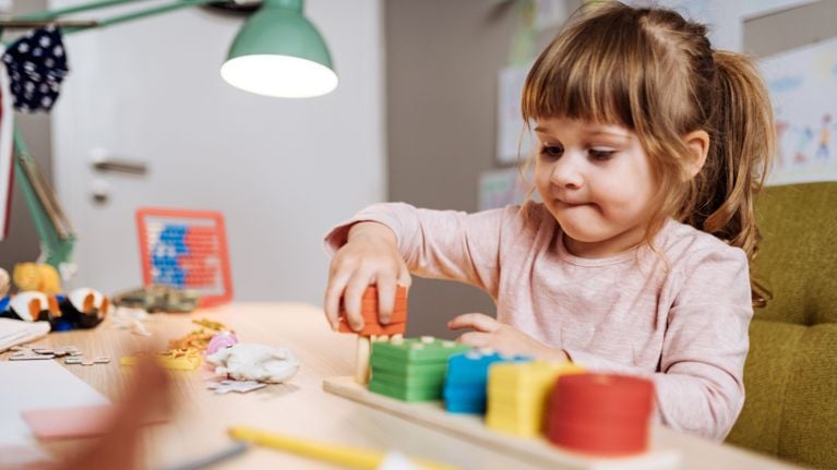 A toddler plays with colourful wooden toys.