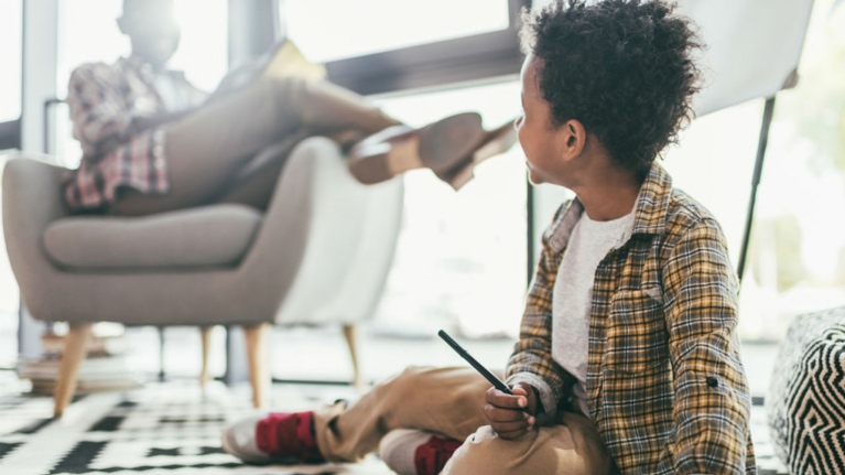 A kid looking at his dad while sketching
