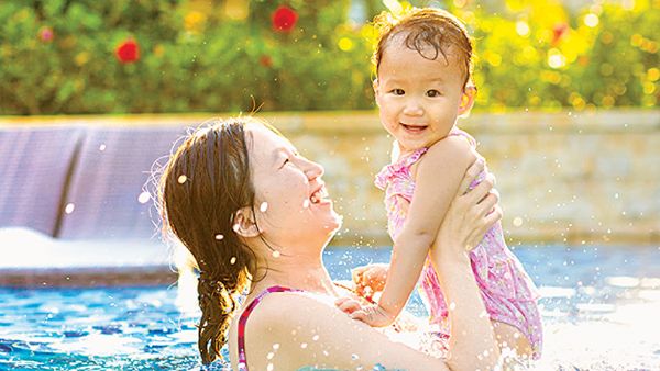 Mom holding up her baby while standing in a pool
