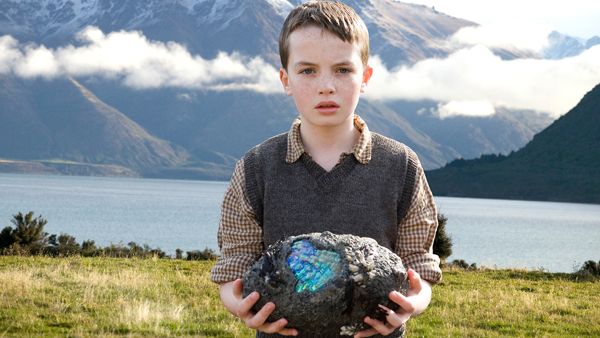 Promo image from The Water Horse Legend of the Deep showing a boy in the mountains near a lake holding a magic egg
