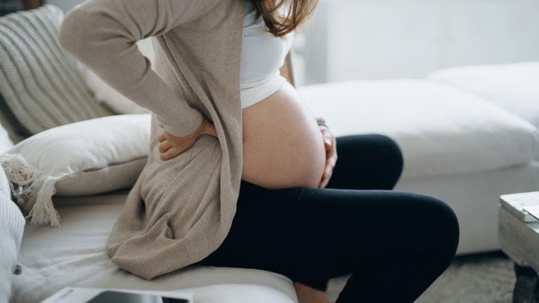 pregnant woman touching her belly and lower back, suffering from backache