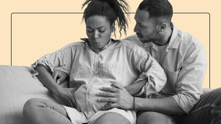 A pregnant woman in the backseat of a car looks like she's going into labour.