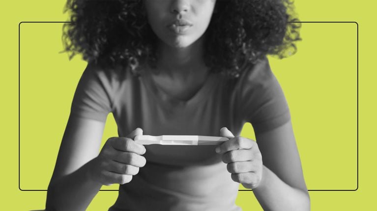 A woman holding a pregnancy test after experiences early pregnancy signs