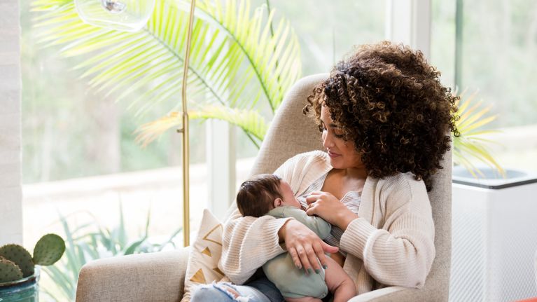 Young mom nurses her newborn baby while in the child's nursery.