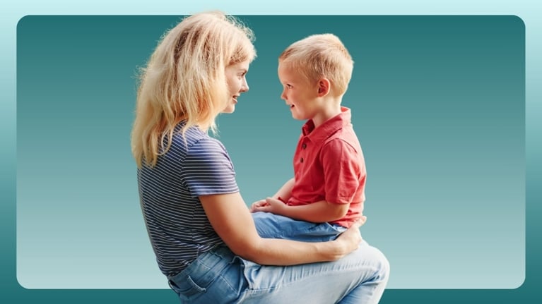 A mother sits on a picnic bench with her young son on her lap, both smiling and making eye contact. This tender moment illustrates how to start early lessons in body boundaries, consent, and curiosity through gentle guidance and age-appropriate responses.