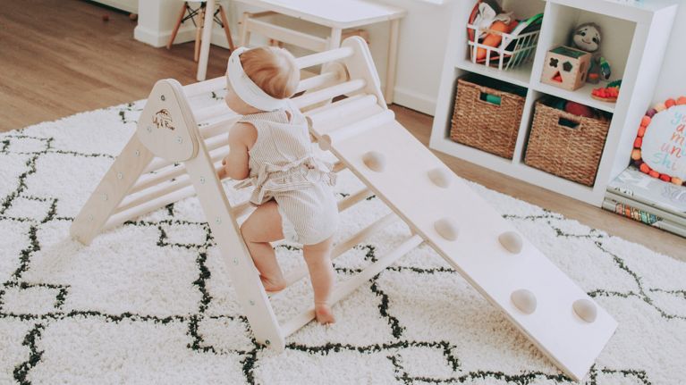 A toddler climbing on a play climber.