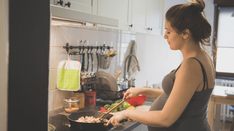 pregnant woman cooking on a stove in the kitchen