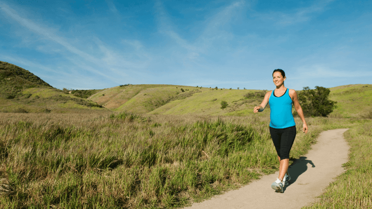 pregnant woman walking on a hiking path outside