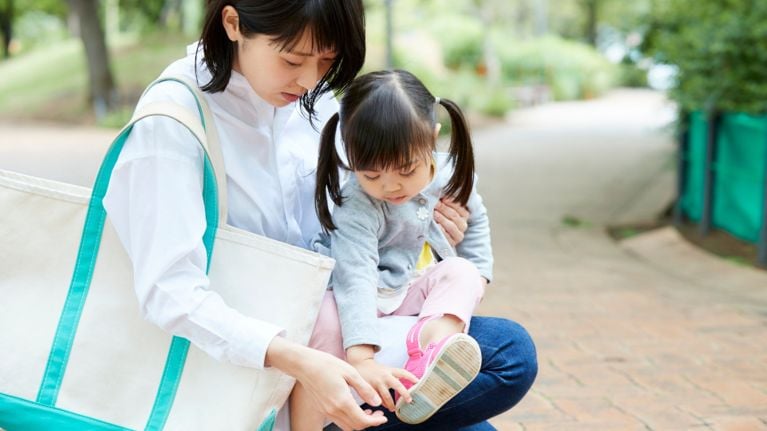 A mom adjusts her daughter's shoe 