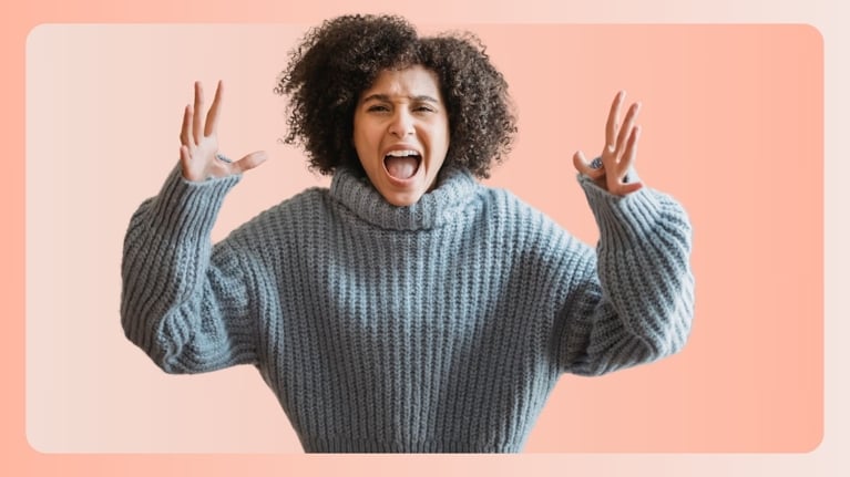 A woman in a chunky sweater raises her hands mid-yell, eyes wide and mouth open in an expression of intense frustration. This image embodies the raw emotional release often associated with “mom rage.”