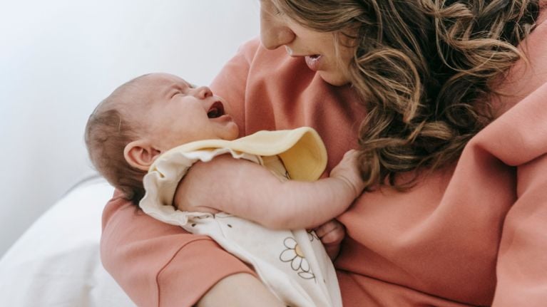 A mother cradles her crying baby. 