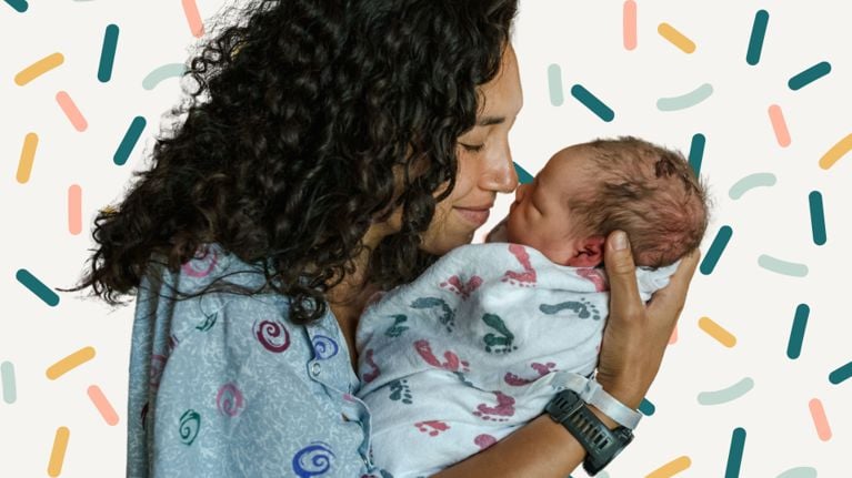 A new mother with curly hair smiles gently while holding her swaddled newborn close. Both wear hospital ID bands, and the background features playful, colorful sprinkles on a cream backdrop.