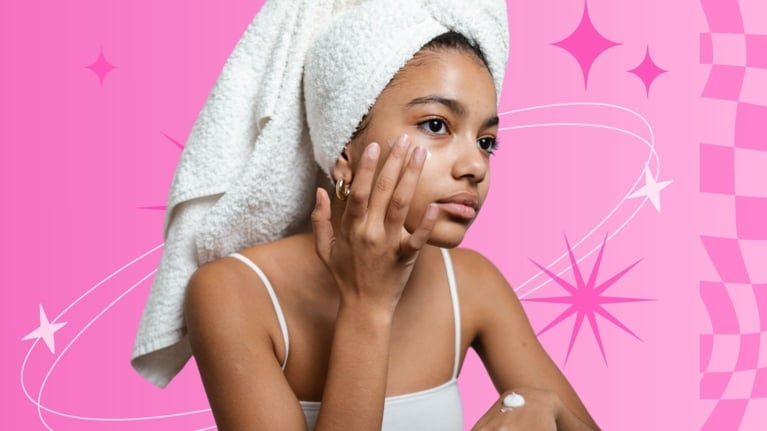 Tween girl in a towel head wrap gently applying skincare cream to her face, against a playful pink background with sparkles and stars.