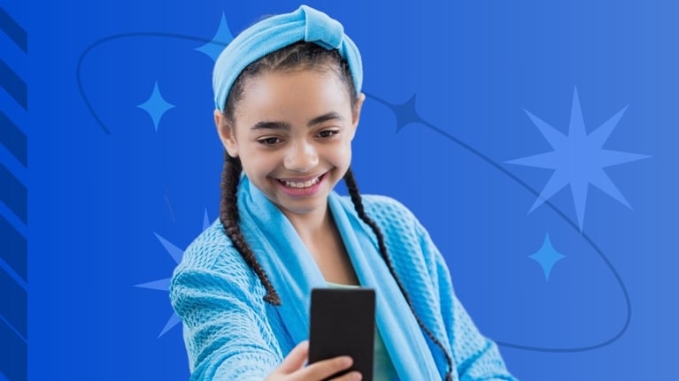 A smiling tween girl wearing a bright blue headband and matching robe takes a selfie with her smartphone against a starry blue background.