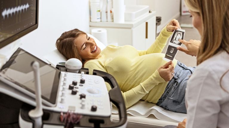 A woman receiving ultrasound photos and smiling