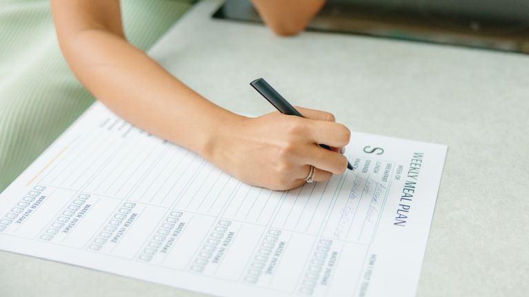 A woman writing on a meal plan sheet