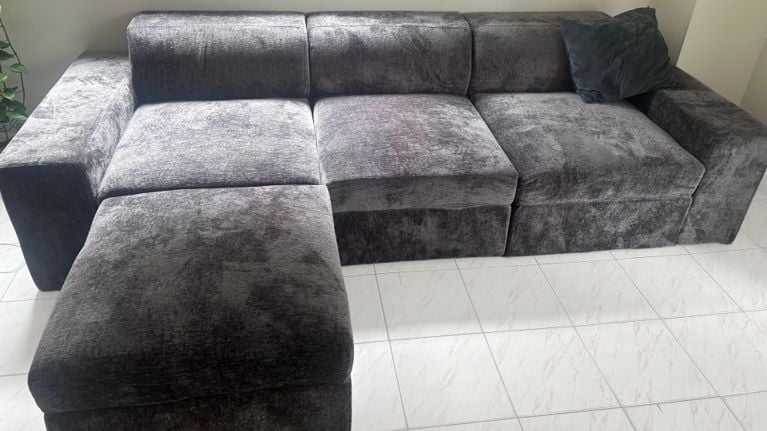 Fully assembled dark grey Cozey Atmosphere sectional couch in a tiled room, showing its plush, modern design.