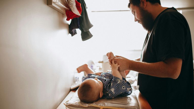 A dad changes his toddler's diaper.