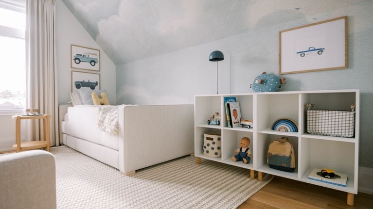 A child's bedroom features a low-rise shelf and paintings of cars.