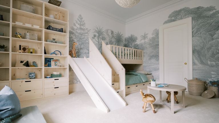 A child's bedroom features a short, wooden slide and a child-sized table set.