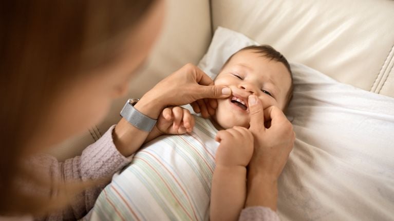 A woman checking the incoming teeth of a baby