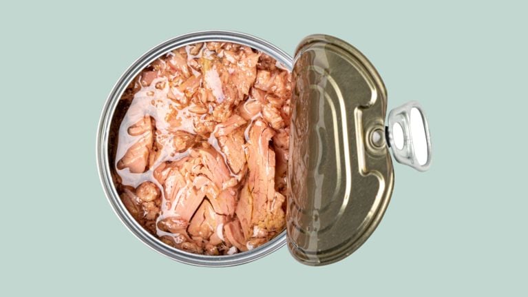 An open can of tuna in water or oil, viewed from above against a pale green background.