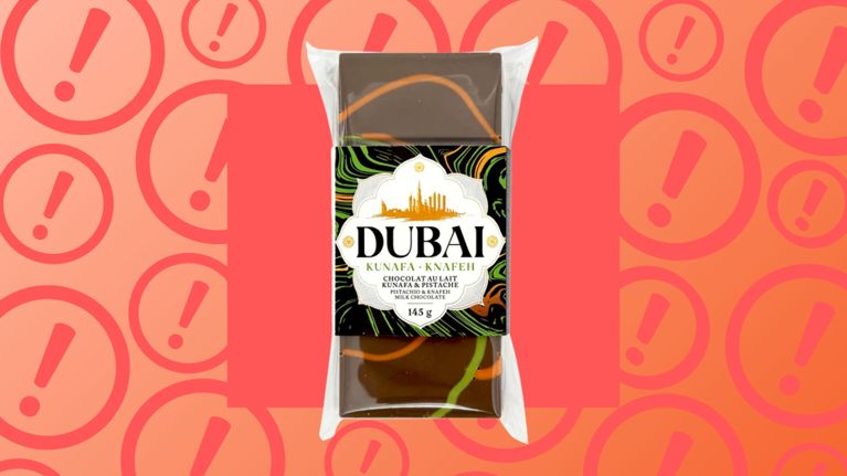 Package of Dubai Pistachio & Knafeh Milk Chocolate against a red-orange background with warning icons. This product has been recalled across Canada due to potential Salmonella contamination.