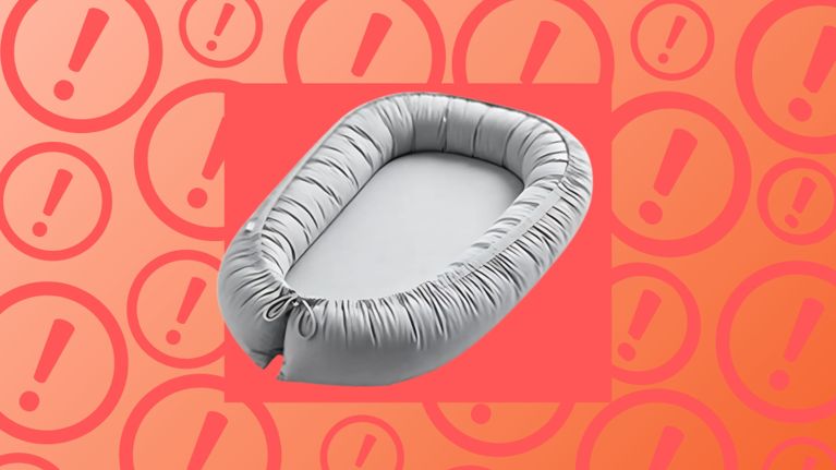 A grey baby lounger with padded sides displayed on a red and orange background with warning icons, representing a product recall due to suffocation risks.