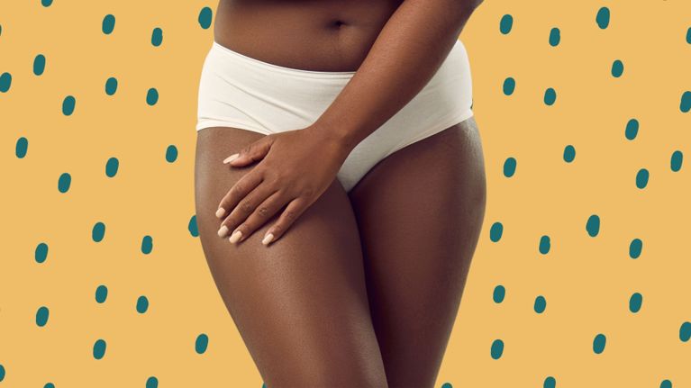 Close-up of a woman’s midsection and upper thighs, wearing cream-colored underwear, with one hand resting gently on her leg. The background is a warm yellow with teal polka dots.