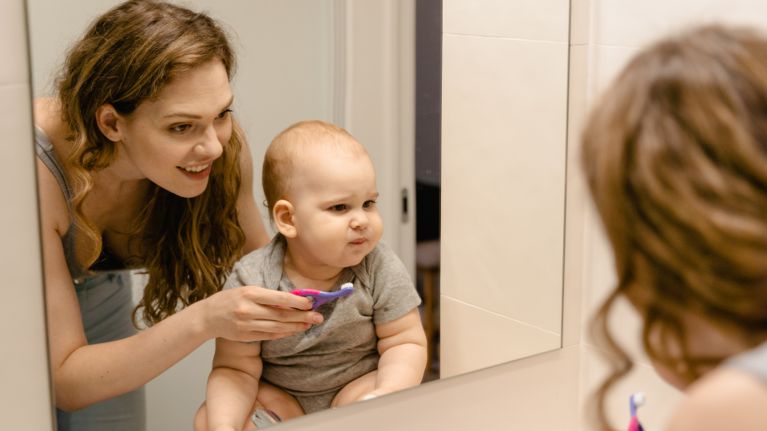 A woman brushing an infant's teeth