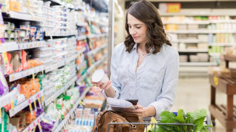 A woman reading the label on a package in a grocery store