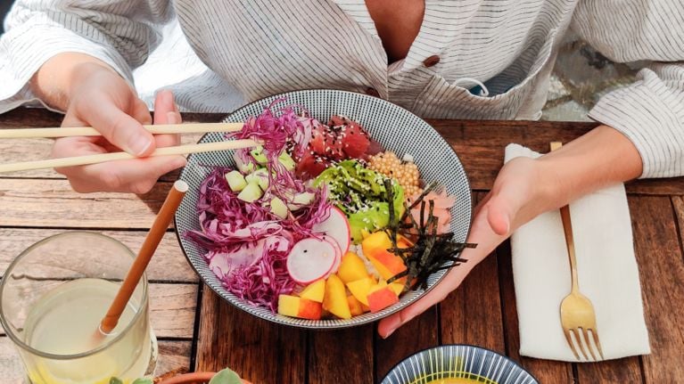 A close-up of a colorful poke bowl filled with vegetables, avocado, tuna, and rice, representing a healthy, nutrient-rich meal for breastfeeding parents.