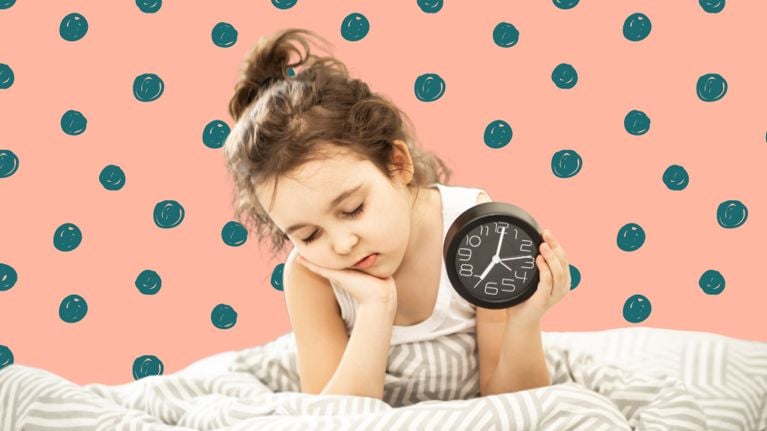 A tired-looking little girl in bed holding an alarm clock with the hands set to 7.