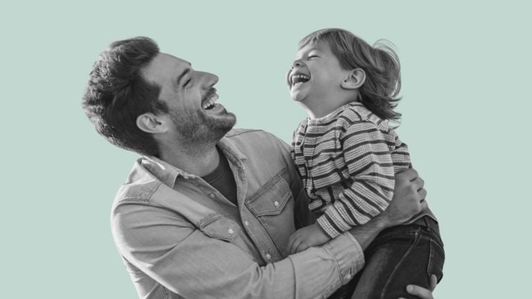 A man holding a young child, both laughing joyfully, set against a light teal background.