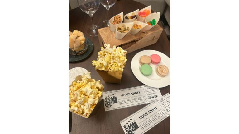 A luxury movie night snack spread featuring popcorn, macarons, and artisanal treats with "Movie Night" tickets.