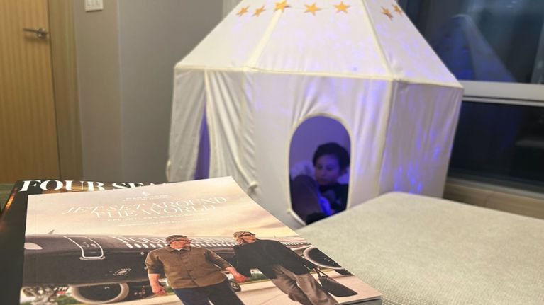 A child relaxes inside a white play tent decorated with stars inside a luxury hotel suite.
