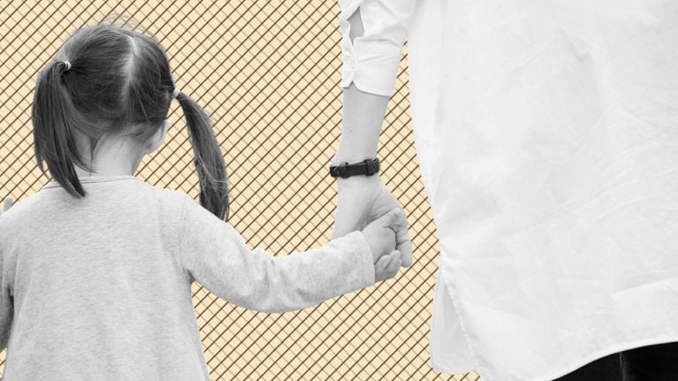 A woman and a young girl holding hands, seen from behind and displayed in black-and-white against a beige background