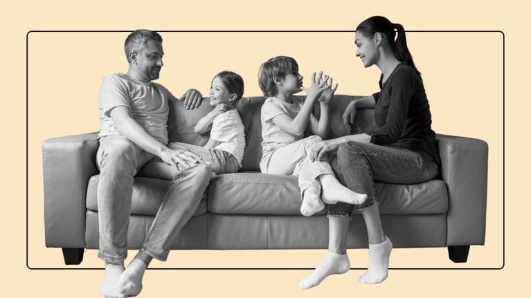A smiling family of four sitting on a sofa, with a father and daughter on the left and a mother and son on the right.