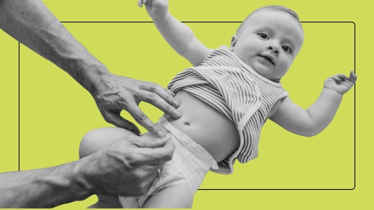 Close-up of a parent's hands changing a baby’s diaper against a green backgroun