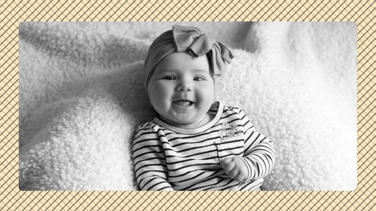 A baby of roughly four months of age with a knit headband and striped top, displayed in black and white in front of a beige graphic