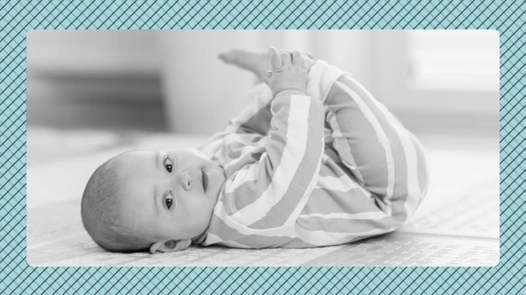 A baby of roughly 5 months of age, lying on its back and holding its ankles while it looks toward the camera, displayed in black and white in front of a blue graphic background
