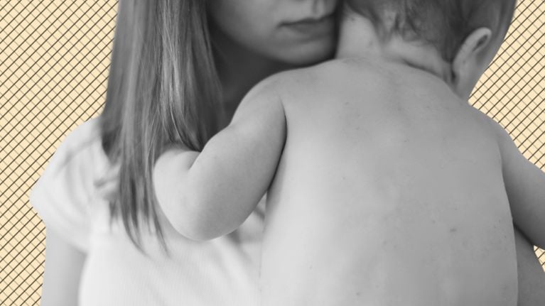 A mother in a white shirt holds a shirtless toddler in her arms.