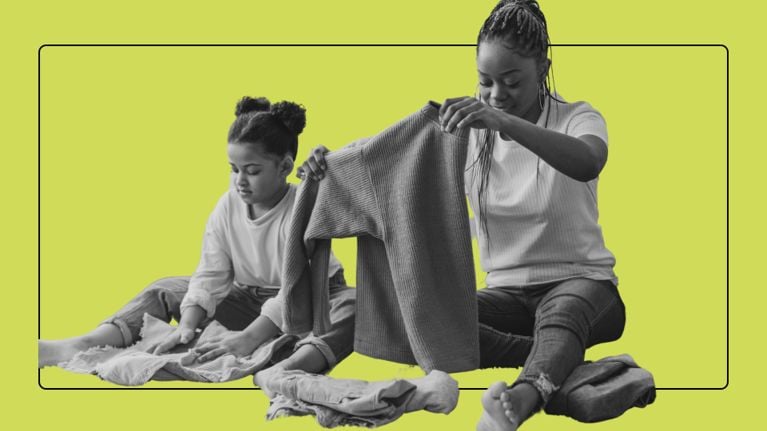 A woman and a girl sit on the floor folding clothes.