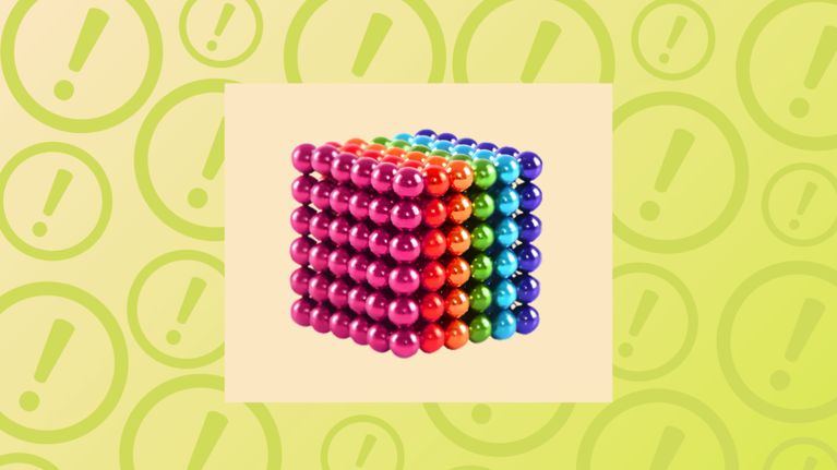 A 6x6 cube of small, multi-colored magnetic balls arranged in rainbow rows on a cream background.